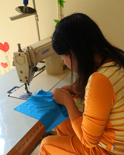 Survivor participating in vocational sewing training through the Power Her Path program.